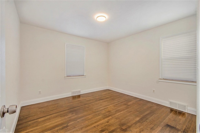 spare room featuring visible vents, baseboards, and wood finished floors