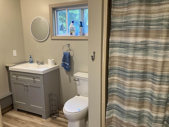 bathroom with toilet, vanity, a shower with curtain, and wood finished floors