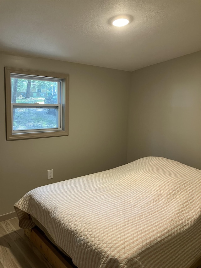 bedroom with wood finished floors and a textured ceiling