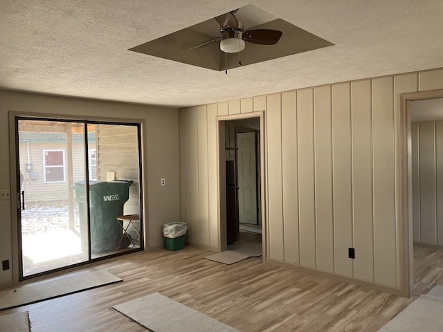 interior space with light wood finished floors, a textured ceiling, ceiling fan, and access to outside