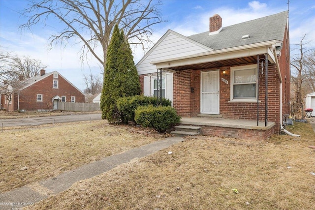 bungalow with a porch, brick siding, and a chimney