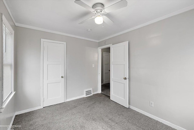 unfurnished bedroom featuring visible vents, baseboards, carpet flooring, and crown molding