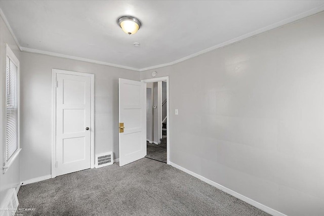 unfurnished bedroom with visible vents, baseboards, carpet, and crown molding