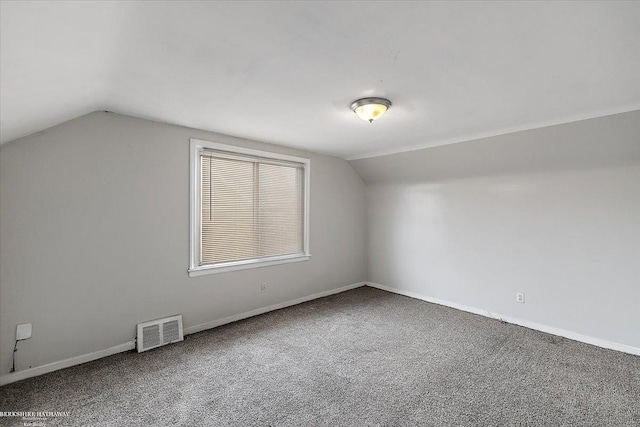 additional living space featuring visible vents, carpet flooring, baseboards, and vaulted ceiling