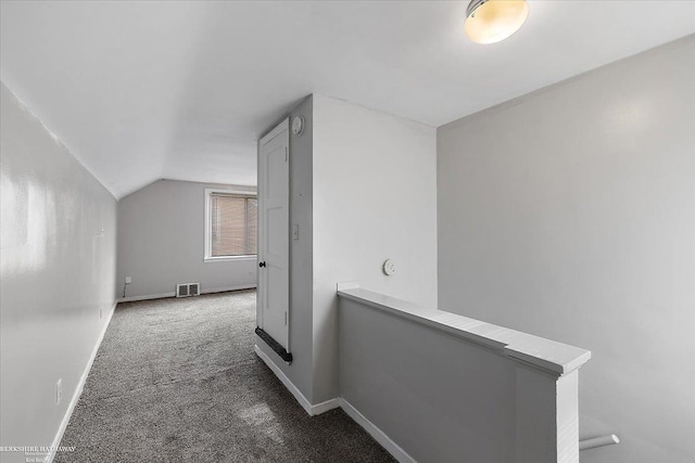 hallway featuring visible vents, baseboards, lofted ceiling, carpet flooring, and an upstairs landing