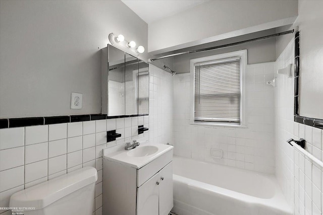 full bathroom with shower / bathing tub combination, toilet, tile walls, and vanity