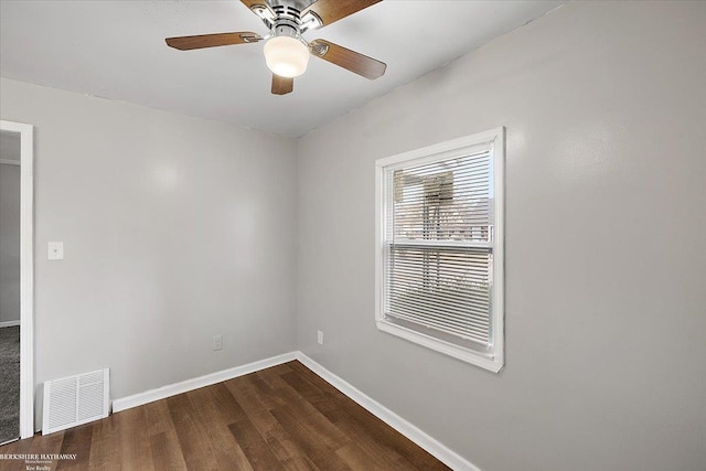 spare room with dark wood-style floors, baseboards, visible vents, and ceiling fan