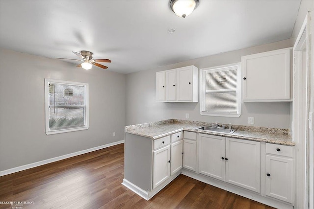 kitchen featuring a sink, baseboards, ceiling fan, white cabinets, and dark wood-style flooring