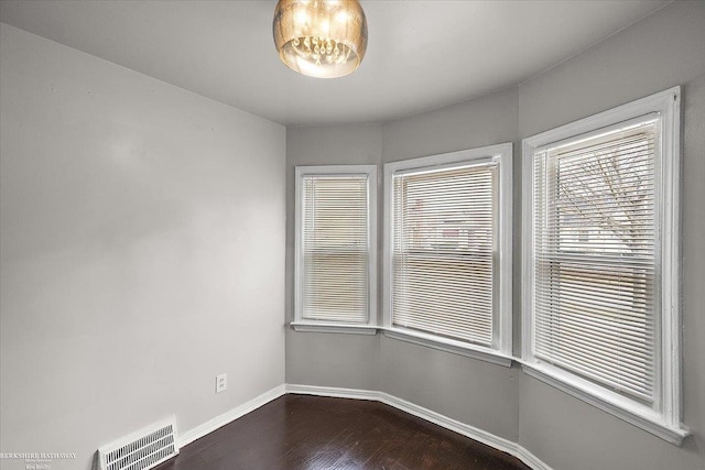 unfurnished room featuring dark wood-type flooring, baseboards, and visible vents