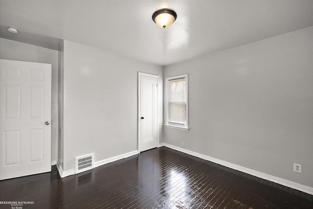 spare room with visible vents, baseboards, and dark wood-style flooring