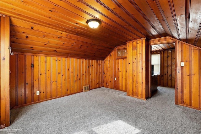 additional living space with visible vents, wooden walls, wood ceiling, and vaulted ceiling