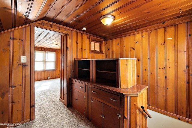 interior space with light colored carpet, wood ceiling, wood walls, and vaulted ceiling