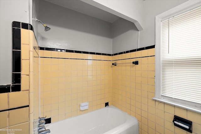 bathroom featuring plenty of natural light, tile walls, and washtub / shower combination