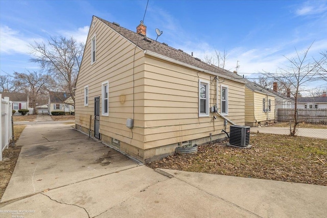 view of side of property with concrete driveway, central AC unit, and fence