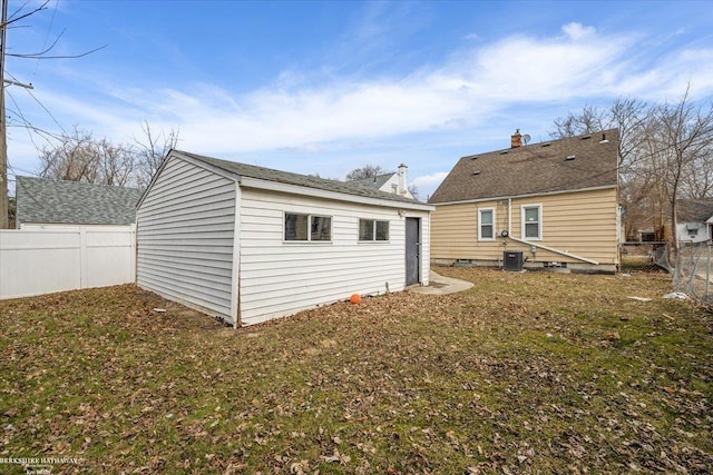 rear view of property featuring an outbuilding, a lawn, cooling unit, and a fenced backyard