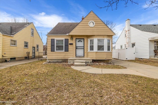 bungalow-style house with a front lawn and fence