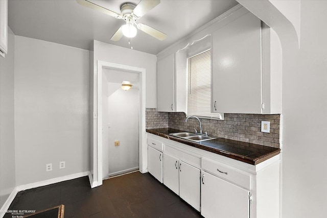 kitchen with white cabinetry, dark countertops, backsplash, and a sink