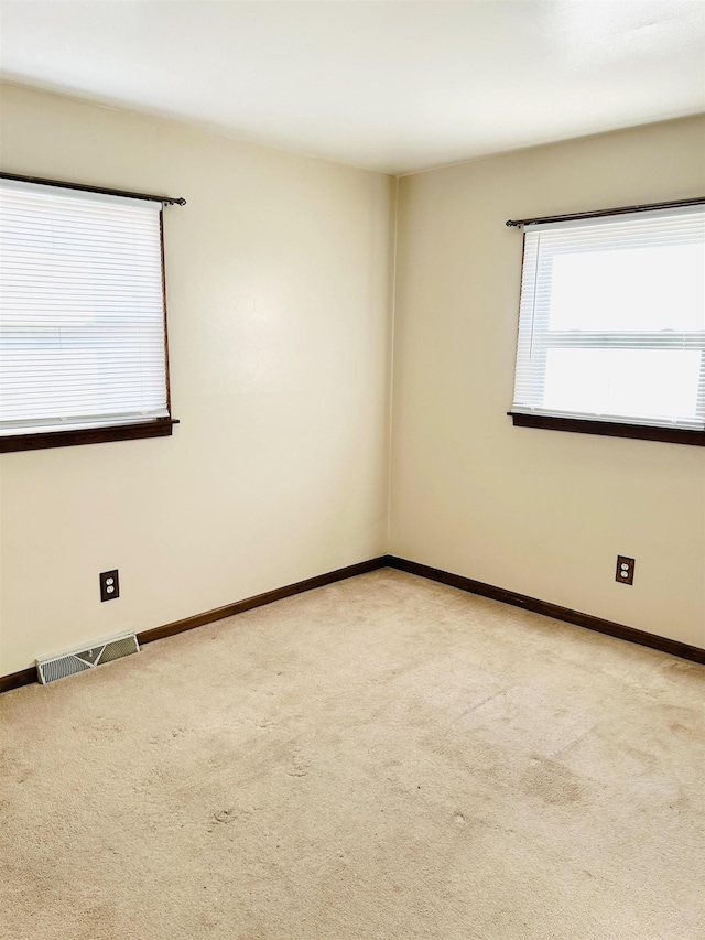 spare room with visible vents, baseboards, and light colored carpet