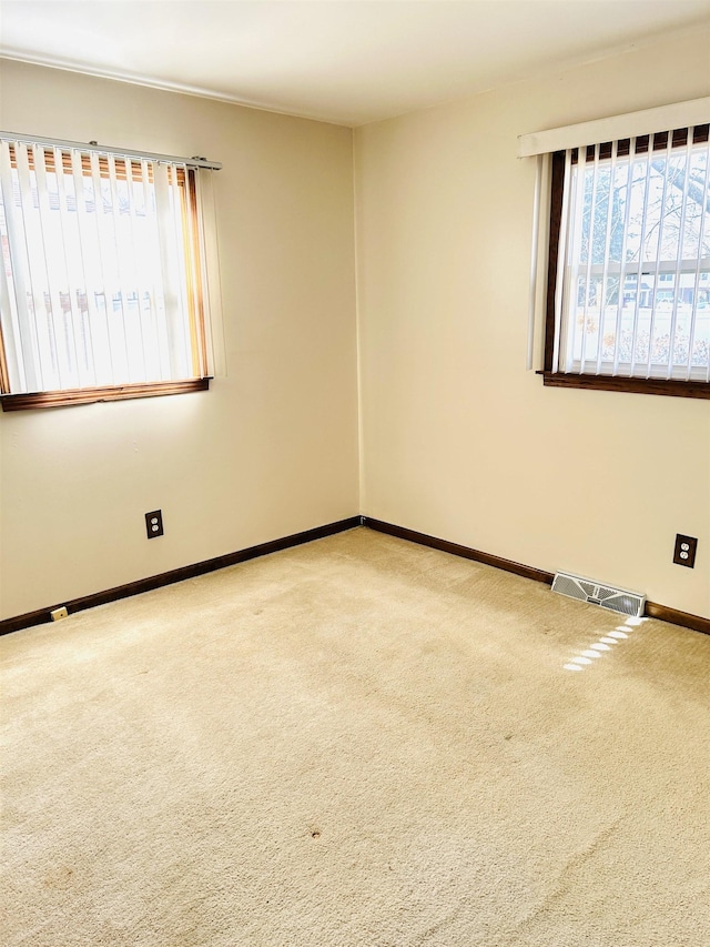 carpeted spare room with visible vents and baseboards