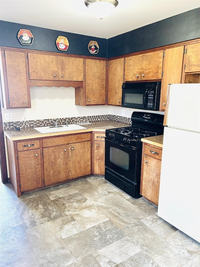 kitchen featuring brown cabinetry, a sink, black appliances, light countertops, and stone finish flooring