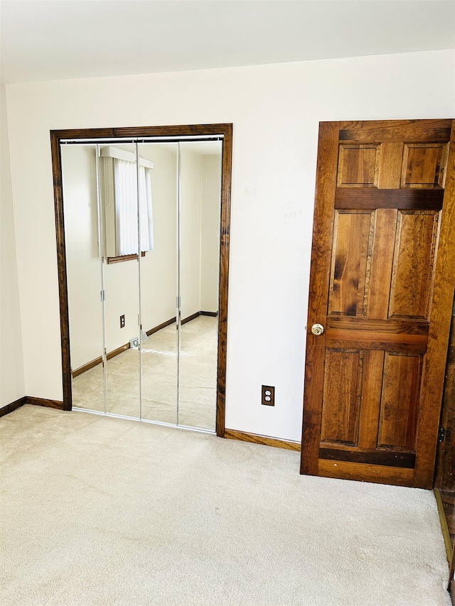 unfurnished bedroom with baseboards, a closet, and light carpet