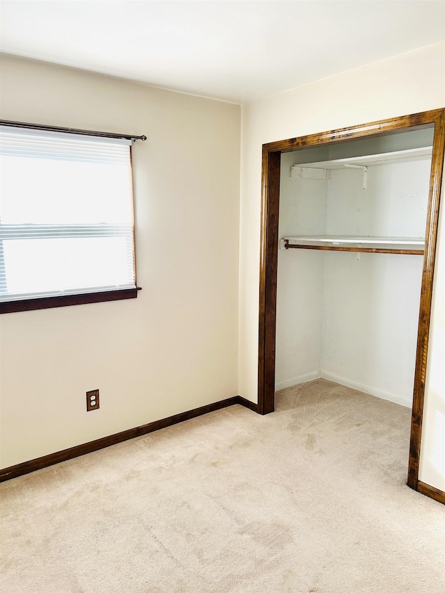 unfurnished bedroom with a closet, baseboards, and carpet