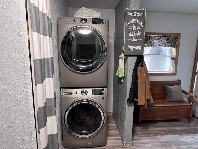 laundry area with stacked washer / dryer, laundry area, and wood finished floors