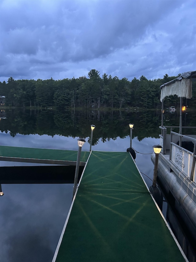 view of tennis court with a forest view and a water view