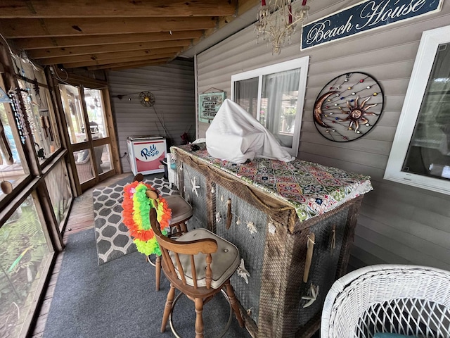 sunroom / solarium featuring vaulted ceiling with beams