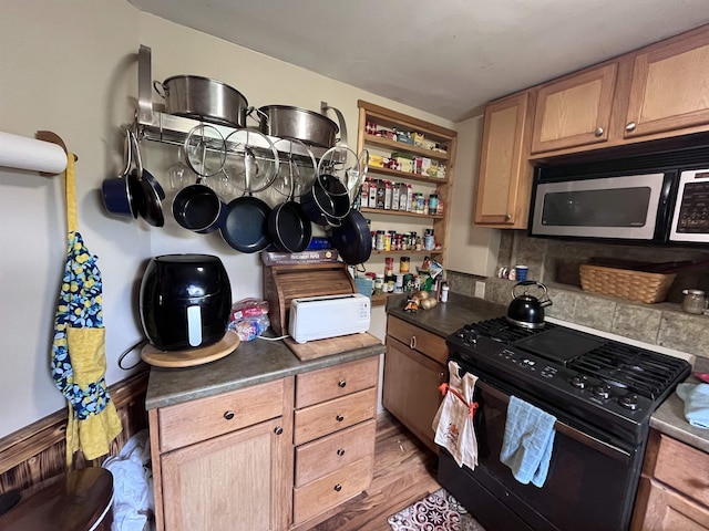 kitchen with gas stove, open shelves, dark countertops, and wood finished floors