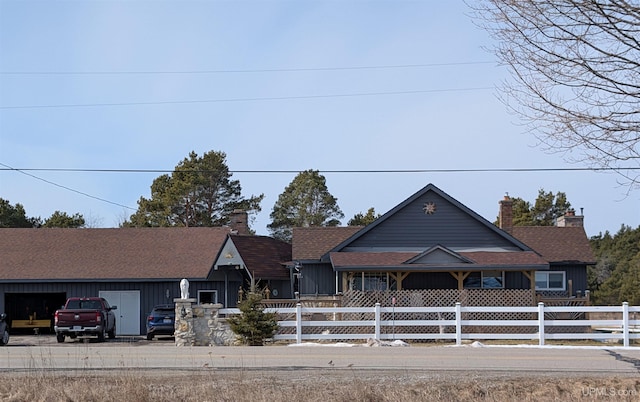 view of front of house featuring driveway, a fenced front yard, and a chimney