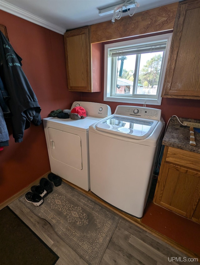 washroom featuring washer and clothes dryer, cabinet space, and wood finished floors