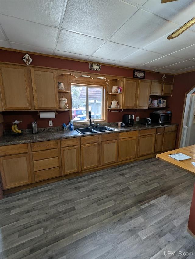 kitchen with dark wood finished floors, a sink, stainless steel microwave, and open shelves