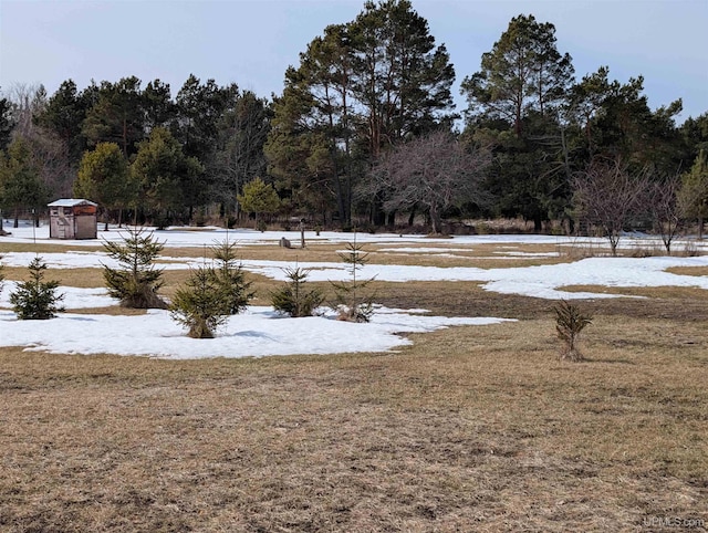 snowy yard featuring a wooded view