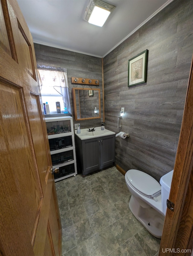 bathroom with toilet, vanity, and ornamental molding