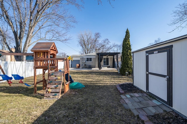 view of yard with an outbuilding, a storage unit, a playground, and fence