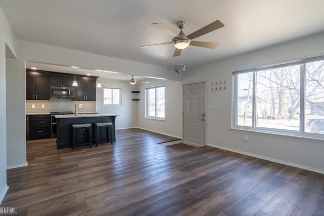 kitchen featuring dark wood finished floors, ceiling fan, stainless steel appliances, light countertops, and open floor plan