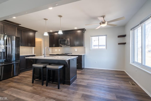 kitchen featuring visible vents, a breakfast bar area, stainless steel appliances, a ceiling fan, and a sink