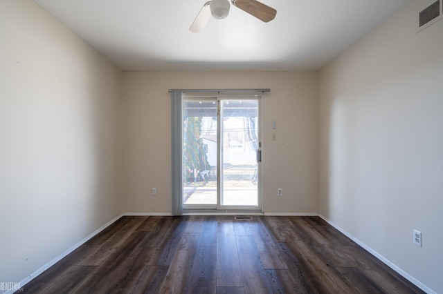 empty room featuring dark wood finished floors, visible vents, a ceiling fan, and baseboards