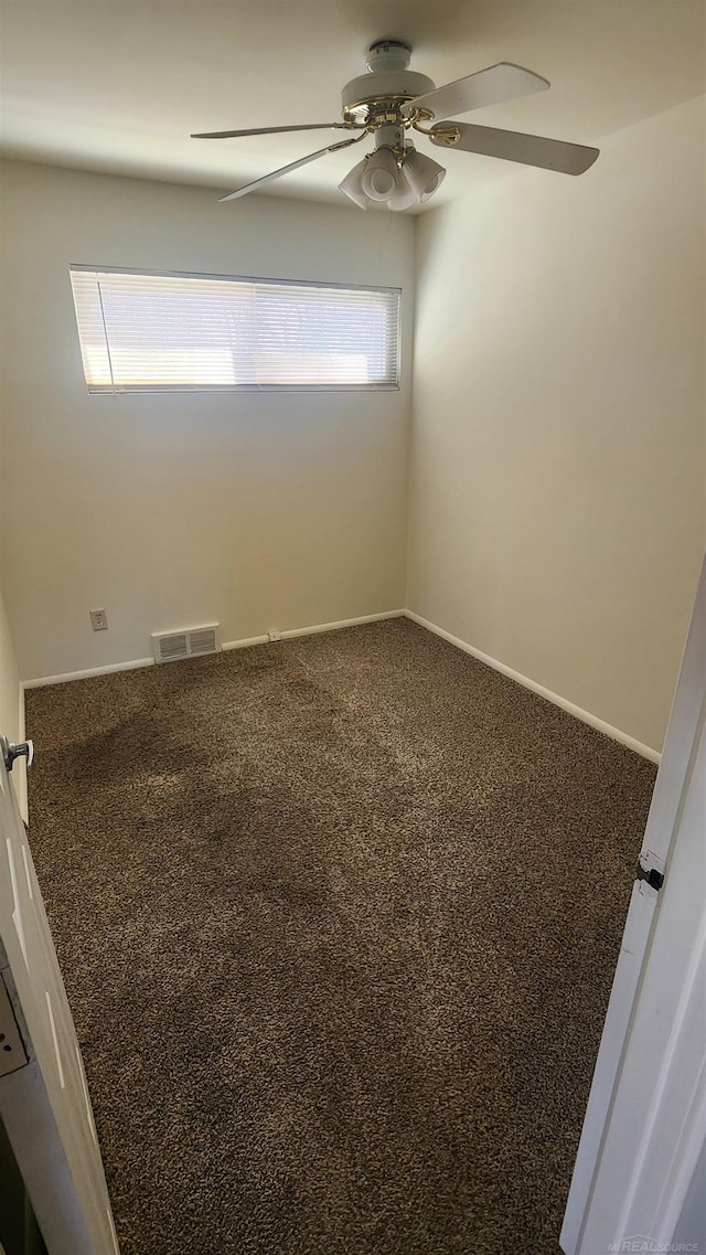 carpeted empty room with baseboards, visible vents, and ceiling fan