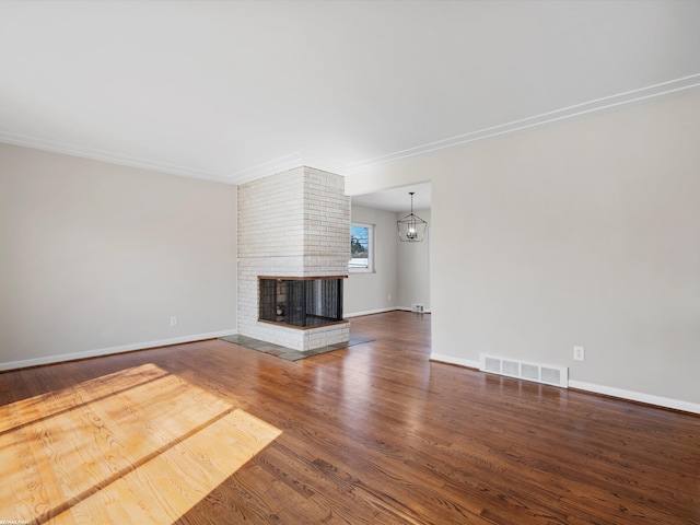 unfurnished living room with a brick fireplace, wood finished floors, visible vents, and baseboards