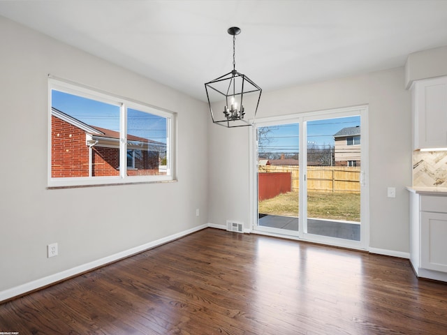 unfurnished dining area with visible vents, baseboards, a chandelier, and dark wood-style flooring