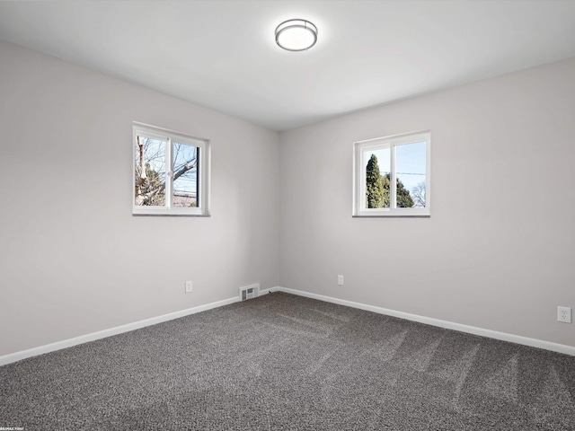 carpeted spare room featuring plenty of natural light, baseboards, and visible vents