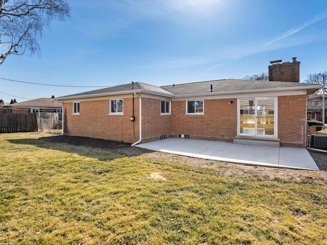 back of property featuring brick siding, fence, a chimney, a yard, and a patio area