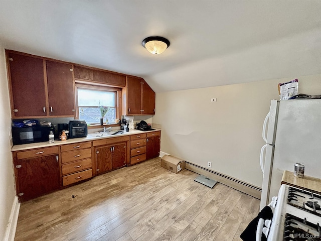 kitchen with light wood finished floors, light countertops, vaulted ceiling, white appliances, and a sink