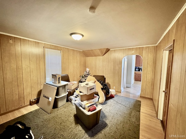 playroom featuring arched walkways, wooden walls, light wood-style flooring, and crown molding