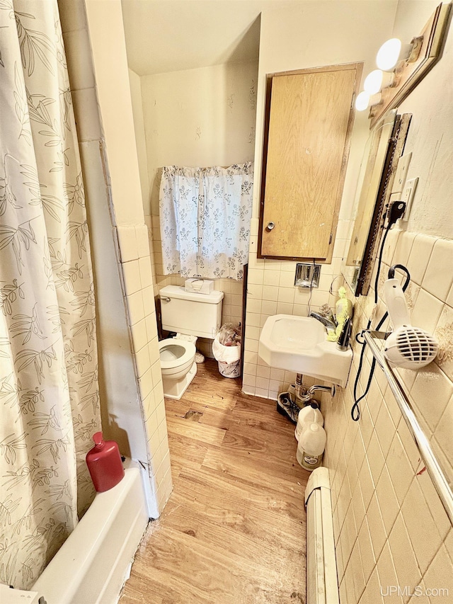 full bathroom featuring a sink, a baseboard radiator, tile walls, and wood finished floors