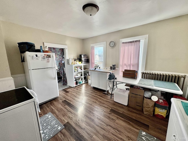 interior space with electric range, wood finished floors, freestanding refrigerator, a breakfast bar area, and light countertops