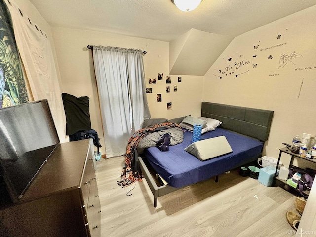 bedroom with lofted ceiling and light wood-style flooring