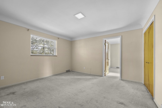 unfurnished room featuring visible vents, light carpet, and baseboards